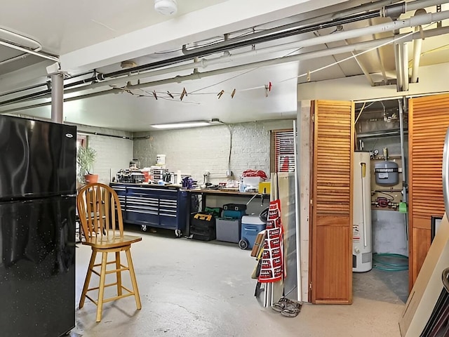 garage featuring freestanding refrigerator, water heater, and a workshop area