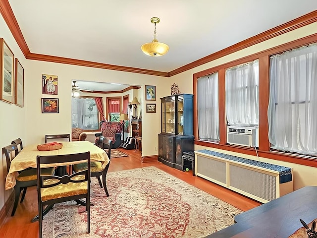 dining space with wood finished floors, radiator heating unit, cooling unit, and crown molding