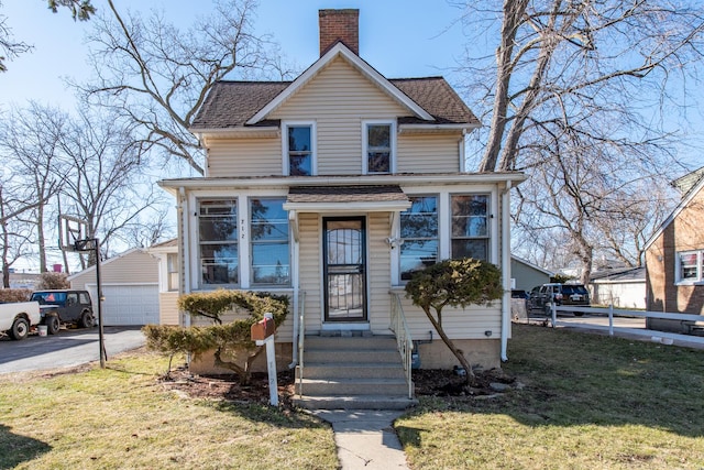 view of front facade with a front yard, an outdoor structure, a chimney, and a shingled roof