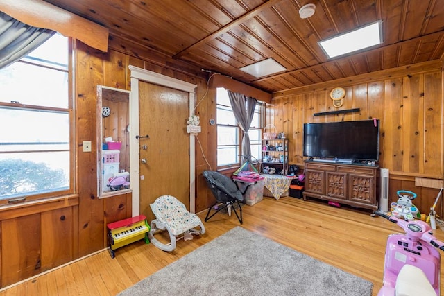 living area featuring a skylight, wood finished floors, wooden walls, and wooden ceiling