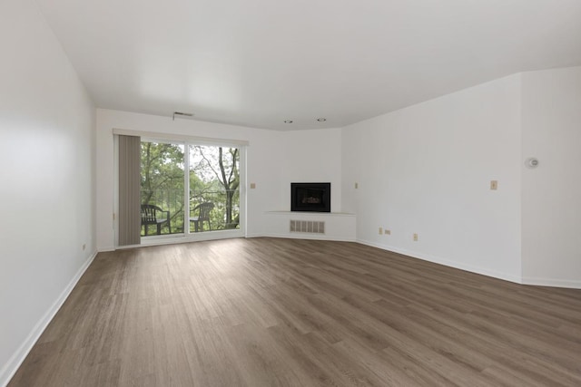 unfurnished living room with baseboards, a fireplace, visible vents, and wood finished floors