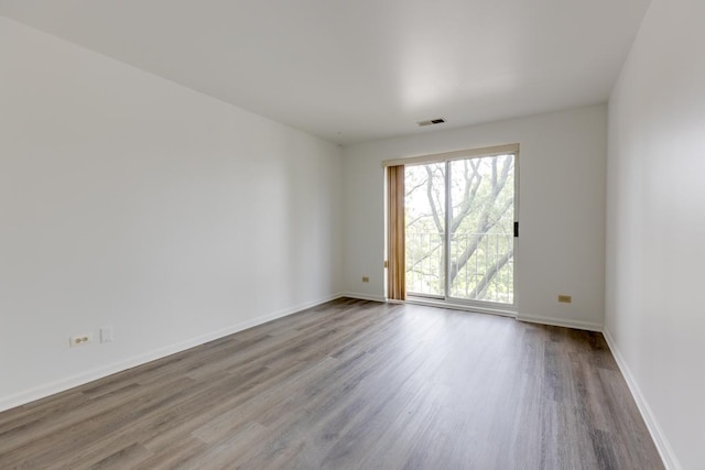 spare room featuring wood finished floors, visible vents, and baseboards