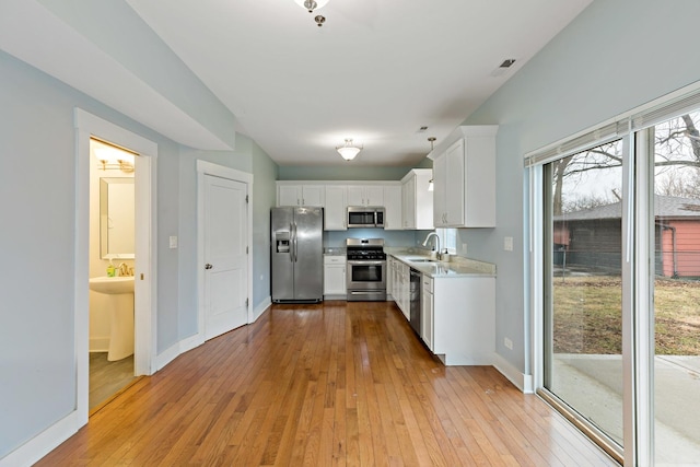 kitchen featuring stainless steel appliances, light wood-style floors, light countertops, and a sink