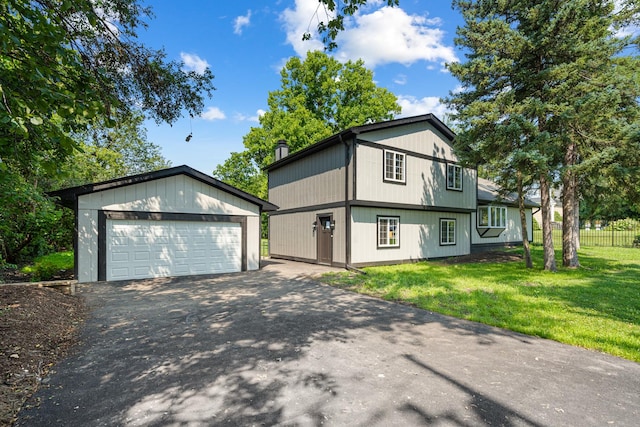 view of front facade featuring a front yard, a detached garage, an outbuilding, and fence