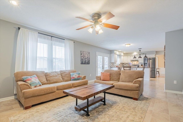 living room featuring french doors, baseboards, and a ceiling fan