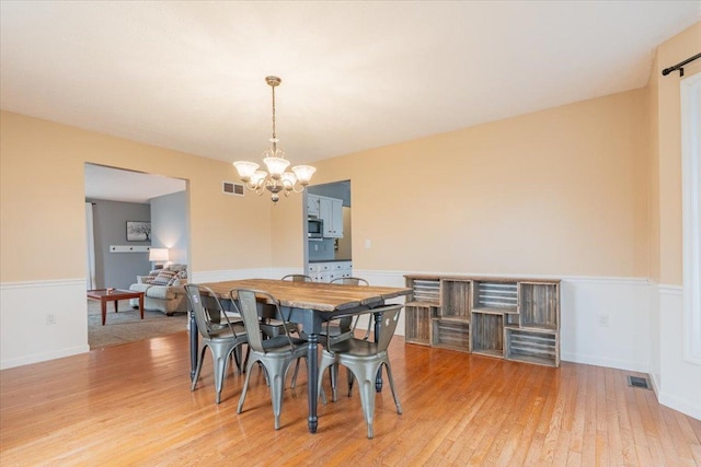 dining room featuring visible vents, an inviting chandelier, and light wood-style flooring