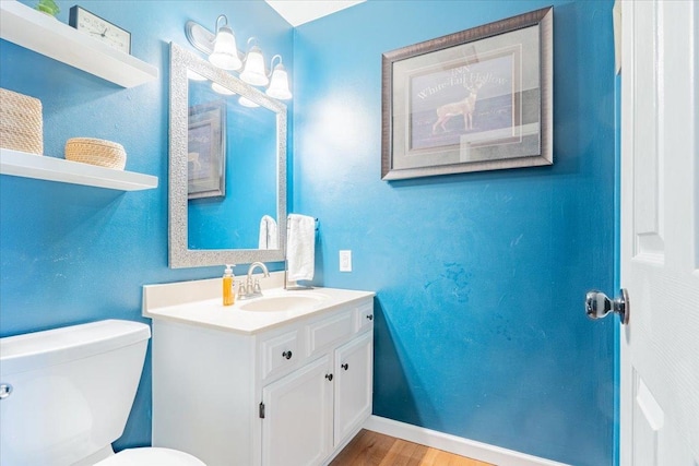 bathroom featuring baseboards, toilet, wood finished floors, and vanity