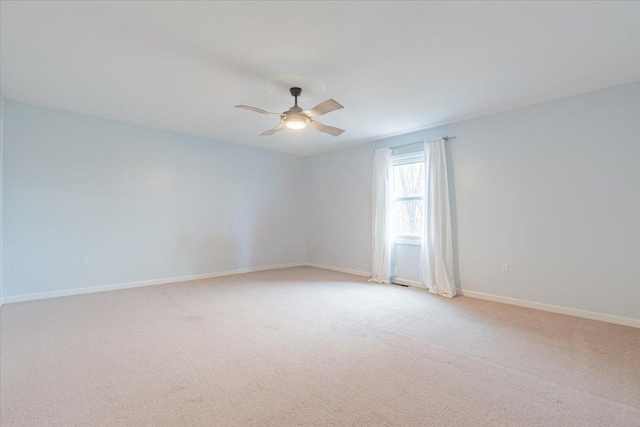 empty room featuring a ceiling fan, light colored carpet, and baseboards