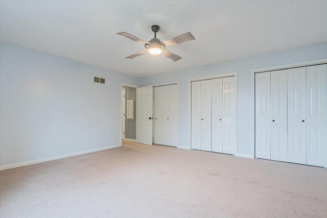 unfurnished bedroom with visible vents, two closets, ceiling fan, baseboards, and light carpet