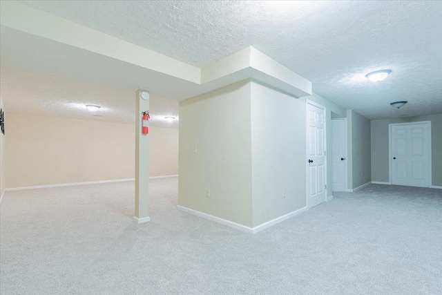 finished below grade area with a textured ceiling, baseboards, and carpet