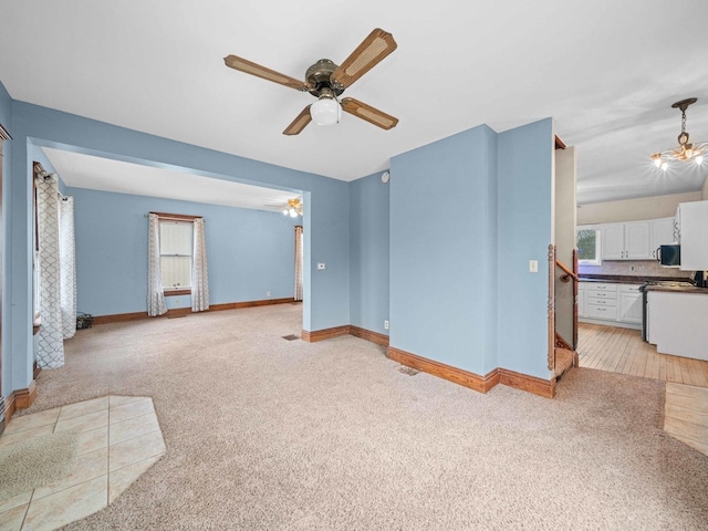 living area with stairway, ceiling fan with notable chandelier, baseboards, and light colored carpet