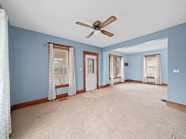 carpeted spare room featuring ceiling fan, visible vents, and baseboards