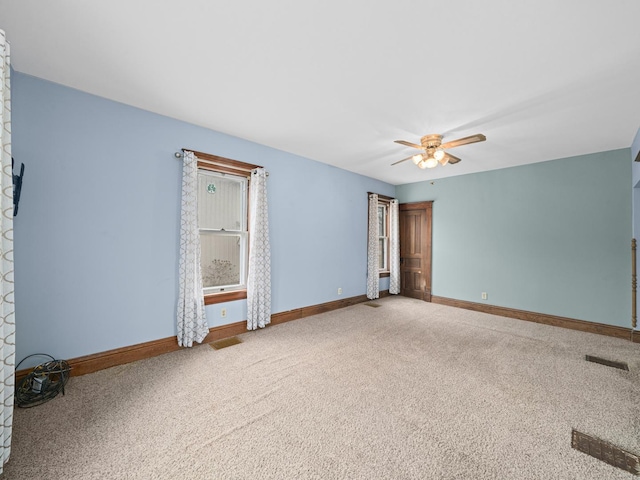 carpeted empty room with ceiling fan and baseboards