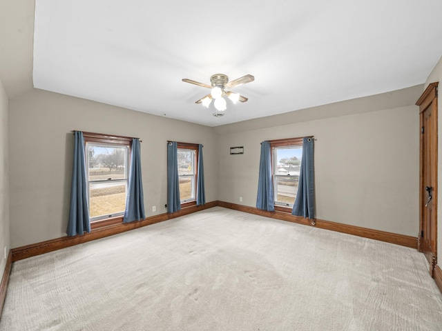 empty room with baseboards, a ceiling fan, and light colored carpet