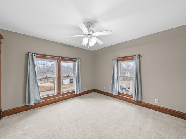 unfurnished room with a ceiling fan, a wealth of natural light, carpet flooring, and baseboards