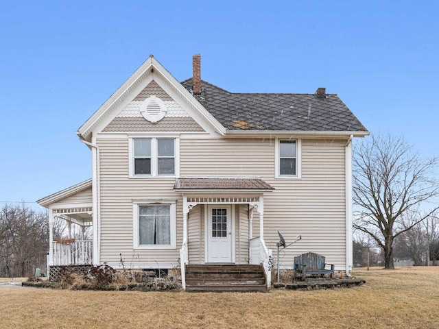 victorian-style house featuring a front yard, a chimney, and entry steps