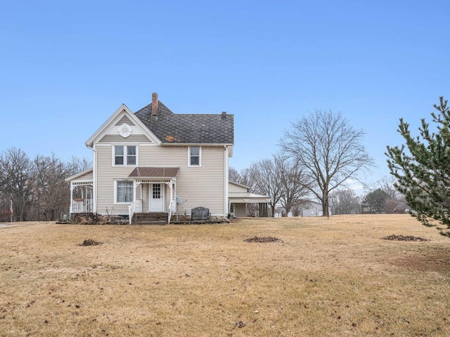 back of house featuring a chimney and a lawn