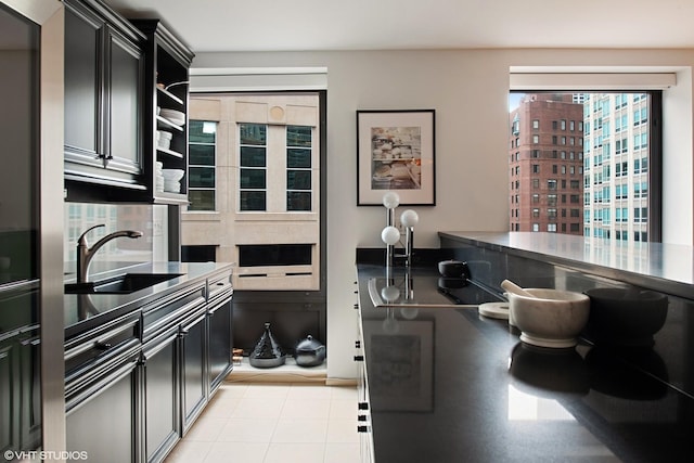 kitchen with a sink, dark cabinets, and light tile patterned flooring