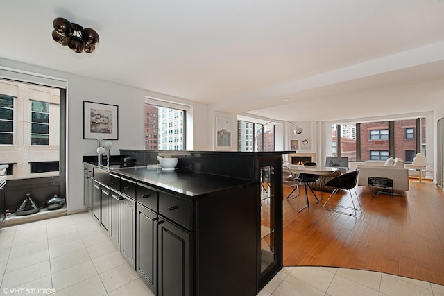 kitchen with dark countertops, open floor plan, light tile patterned floors, a peninsula, and dark cabinets