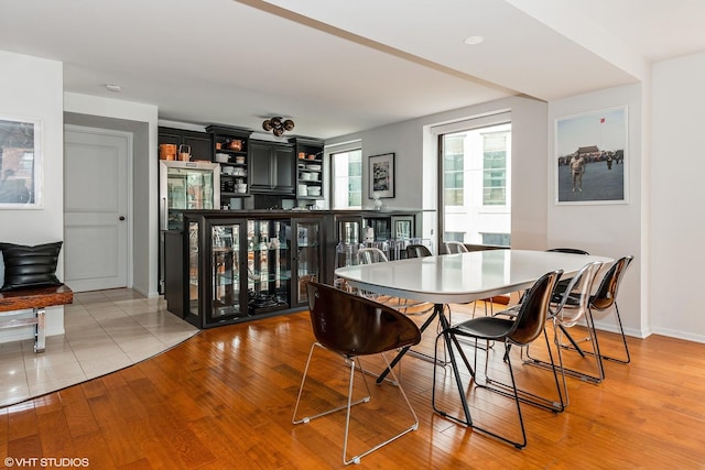 dining space with a bar, light wood-type flooring, and baseboards