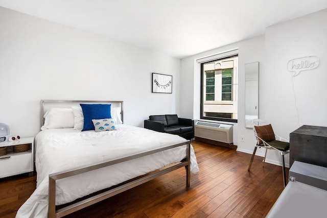 bedroom featuring hardwood / wood-style floors, baseboards, and a wall mounted AC