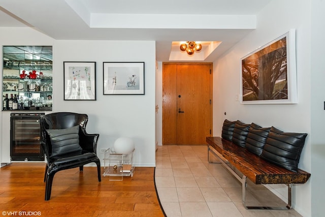 entrance foyer with light wood-style floors, a tray ceiling, a bar, and beverage cooler