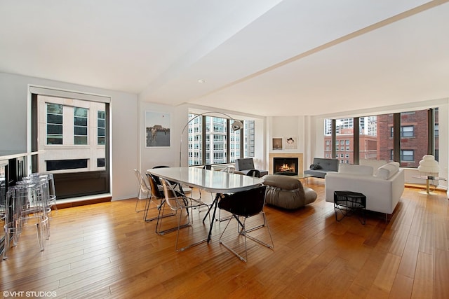 dining space featuring a warm lit fireplace and light wood-style flooring