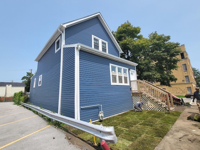 view of side of property with uncovered parking and a yard