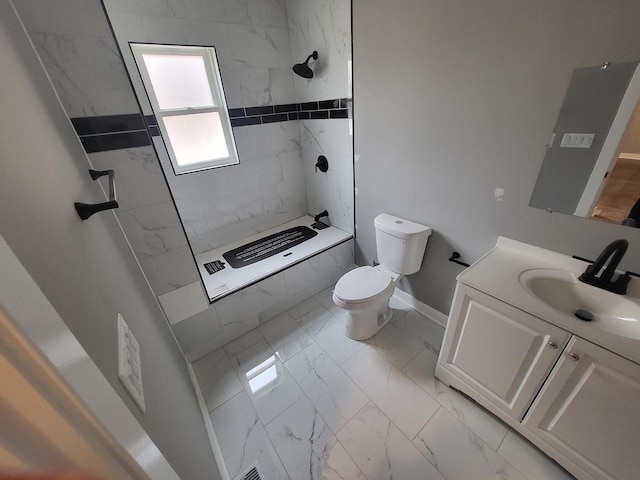 full bathroom with marble finish floor, toilet, a tile shower, vanity, and baseboards
