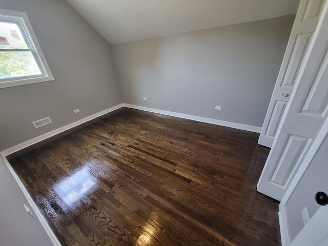 additional living space featuring lofted ceiling, dark wood-style floors, baseboards, and visible vents