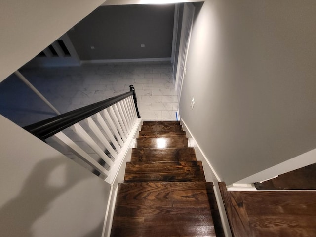 stairway with marble finish floor and baseboards