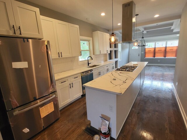 kitchen with a center island, decorative backsplash, appliances with stainless steel finishes, a sink, and light stone countertops