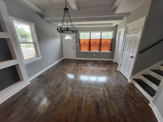 unfurnished dining area featuring baseboards, stairway, dark wood-type flooring, an inviting chandelier, and beam ceiling