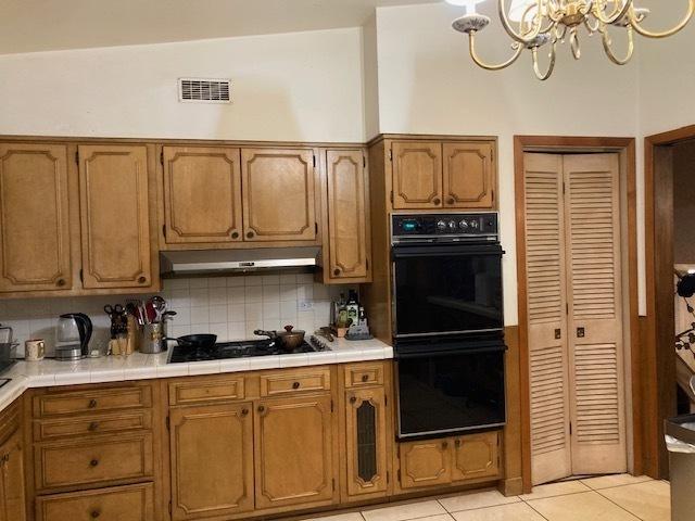 kitchen with visible vents, decorative backsplash, light tile patterned flooring, under cabinet range hood, and black appliances