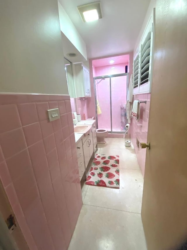 full bath with toilet, a wainscoted wall, vanity, tile walls, and a shower stall