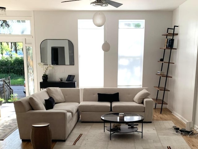 living room with baseboards, light wood finished floors, and ceiling fan