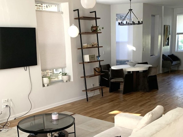 living area featuring baseboards, a notable chandelier, and wood finished floors