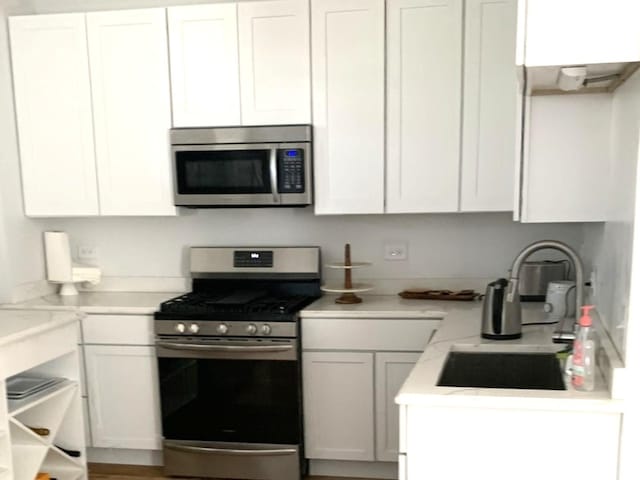 kitchen with white cabinets, appliances with stainless steel finishes, light countertops, and a sink