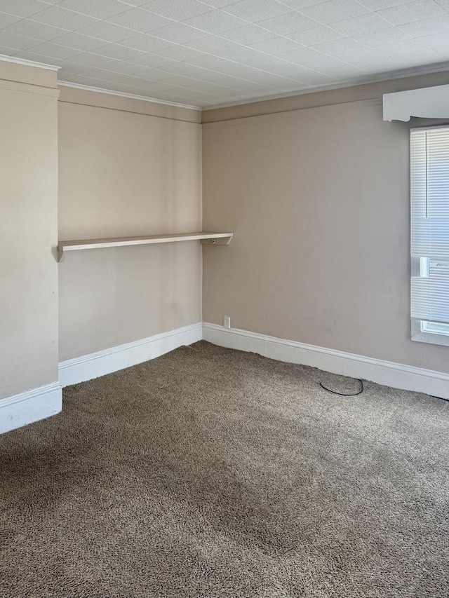 empty room featuring crown molding, baseboards, and carpet floors