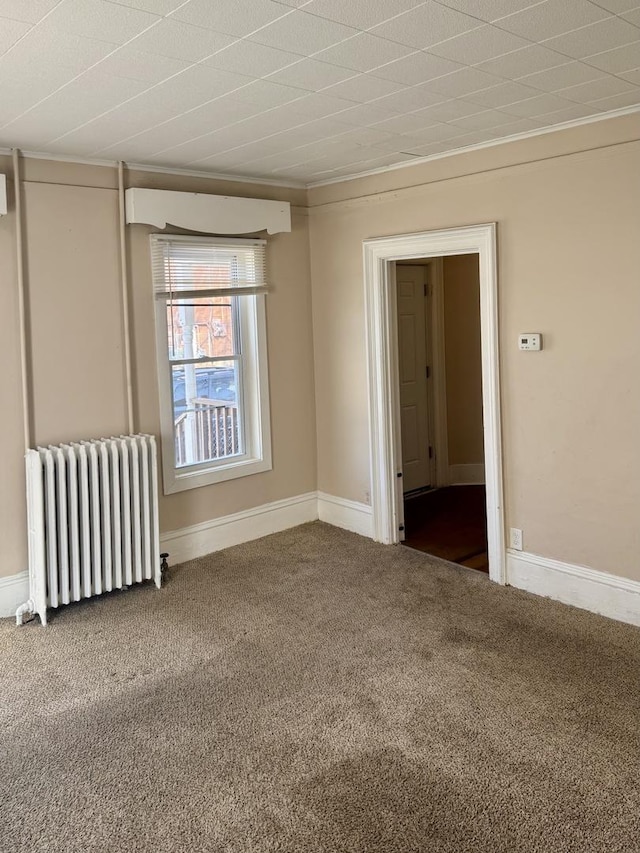 carpeted spare room featuring radiator, baseboards, and ornamental molding