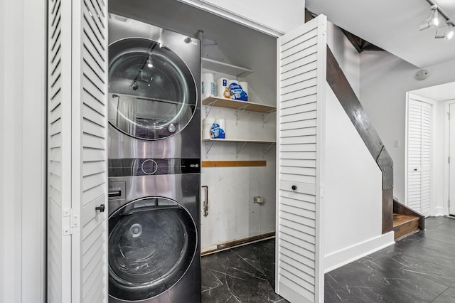 laundry room with stacked washer / dryer, marble finish floor, rail lighting, and laundry area