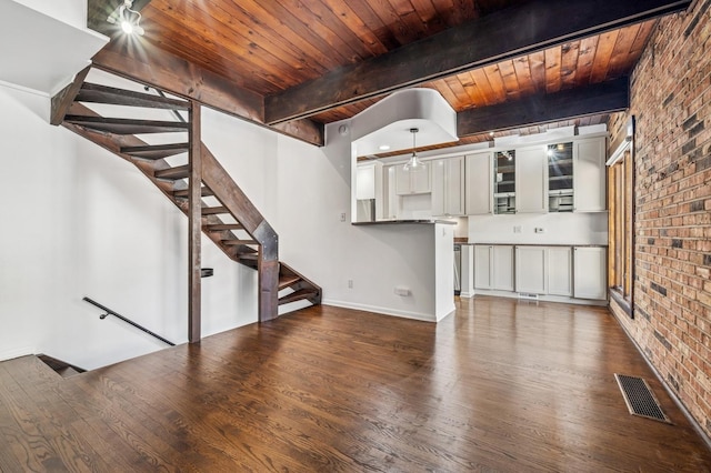 unfurnished living room featuring visible vents, brick wall, wood ceiling, beam ceiling, and wood finished floors