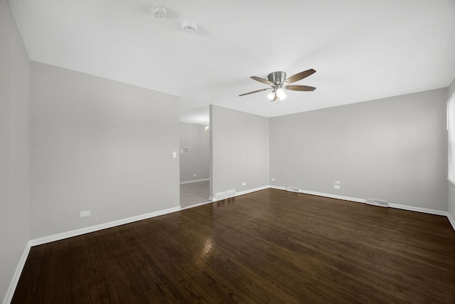 spare room featuring visible vents, baseboards, dark wood-type flooring, and ceiling fan