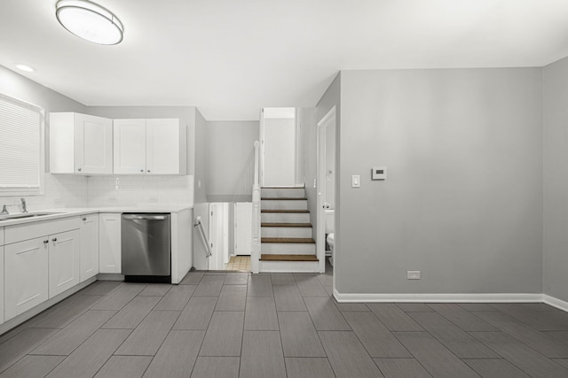 kitchen featuring decorative backsplash, white cabinets, dishwasher, and a sink