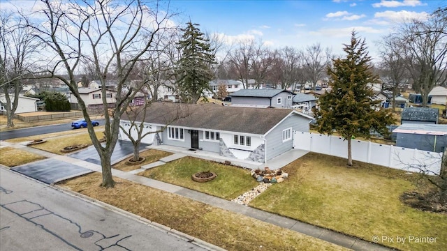 view of front of home with a residential view, driveway, a front lawn, and fence