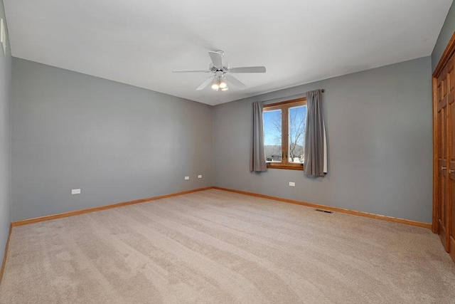 spare room with a ceiling fan, visible vents, carpet, and baseboards