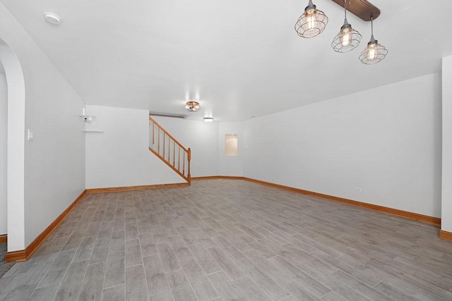 interior space with arched walkways, stairway, light wood finished floors, and baseboards