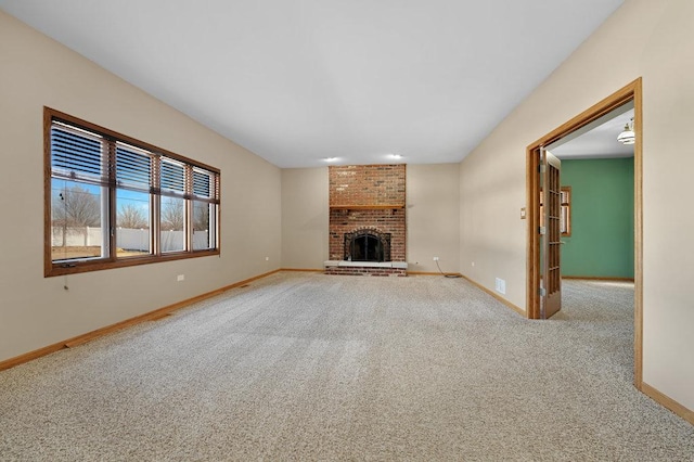 unfurnished living room featuring a brick fireplace, baseboards, and carpet