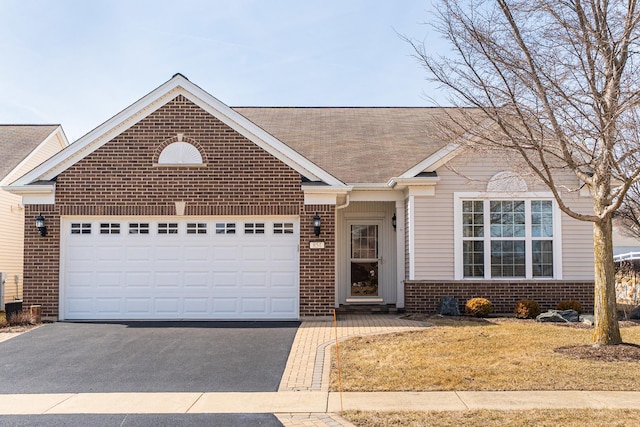 single story home featuring aphalt driveway, brick siding, a garage, and a front yard