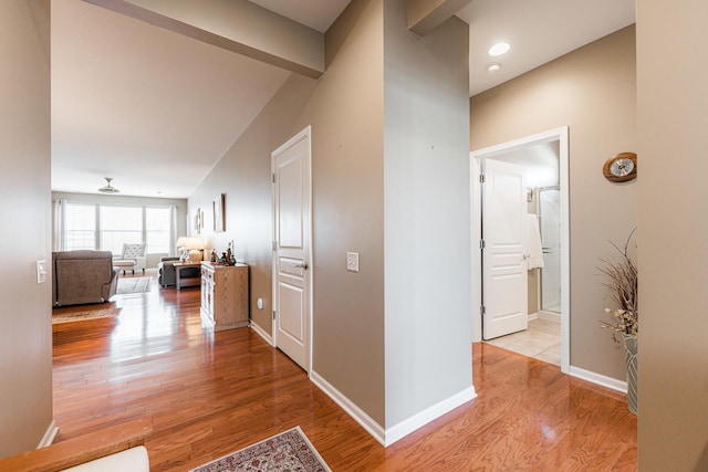 corridor featuring baseboards and light wood finished floors